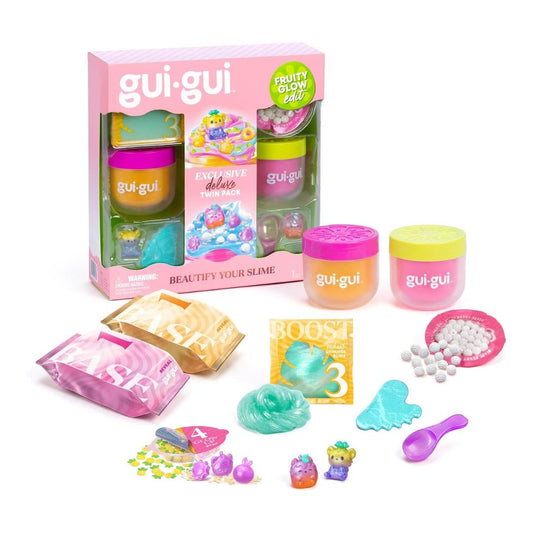 A gui-gui Slime Deluxe toy set displayed with its pink retail box and scattered contents on a white background. The set includes multiple colorful slime jars, packets, small accessories, beads, and a box of boost powder.