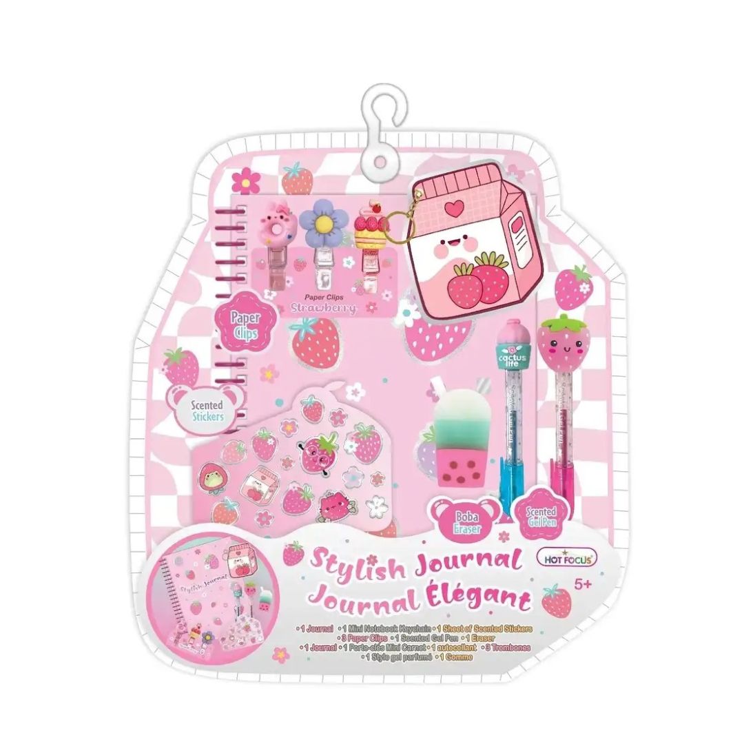 A pink and white strawberry-themed stationery gift set in a hanging plastic package, featuring a journal, pens, stickers, and small accessories with cute cartoon illustrations.
