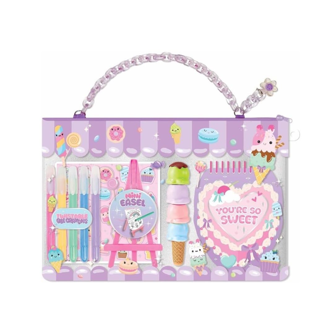 A pastel purple and pink toy art set in a clear zippered case with a chain handle, decorated with cute illustrations of cupcakes, ice cream cones, and sweets. The set includes colored pencils, a mini easel, a heart-shaped notebook, and small toy accessories.