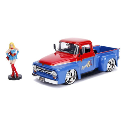 A die-cast metal model of a classic 1957 Chevy pickup truck in red and blue with chrome wheels, shown next to a small figurine of a blonde woman in a blue and red outfit on a white background.