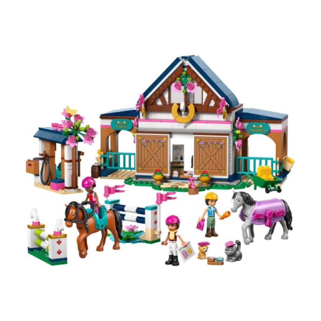 A toy building block set featuring a horse stable with a decorated roof, a small stable accessory area, a jumping fence, and several small minifigures with horses, shown on a plain white background.