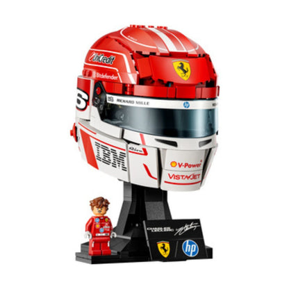 A red and white Ferrari-themed building block model of a racing helmet on a black display stand, with a small red driver minifigure and branded decals included, shown on a plain white background.