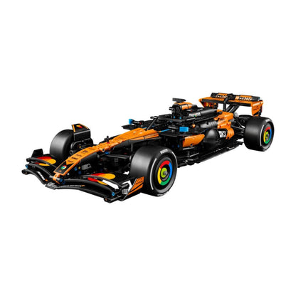 A toy model of a McLaren F1 race car built from interlocking blocks, featuring its signature orange and black livery with colorful wheel details, shown on a solid white background.