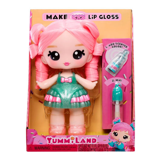 Yummi Land doll with pink hair in a green and pink dress, shown in its retail packaging with a lip gloss applicator and colored liquid inside a pink box.
