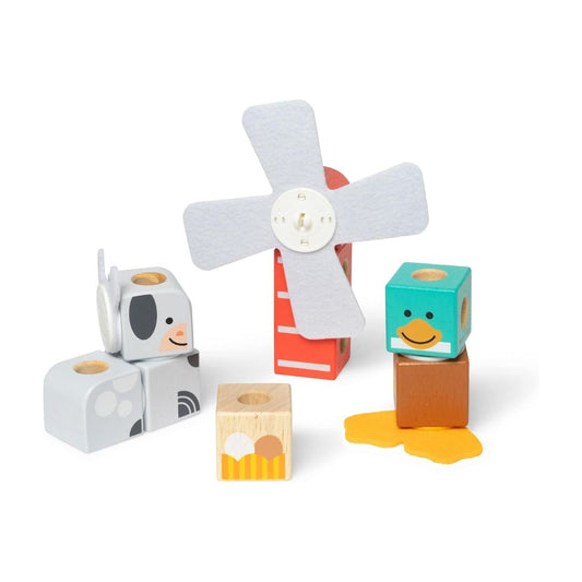 A set of wooden toy blocks and a small windmill on a clean white background. The set includes a gray cow block, a red and white ladder block, a teal duck block, a brown block, a yellow puddle block, and a small wooden farm block.