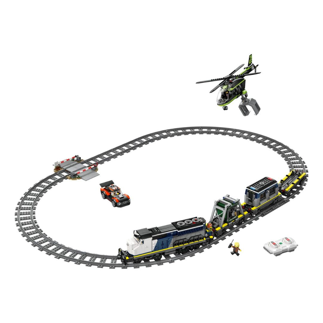 A toy construction set featuring a curved gray train track with a blue and white locomotive, a cargo car, a small orange vehicle, a green and black helicopter, a bridge, and a minifigure, all arranged on a plain white background.