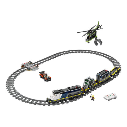 A toy construction set featuring a curved gray train track with a blue and white locomotive, a cargo car, a small orange vehicle, a green and black helicopter, a bridge, and a minifigure, all arranged on a plain white background.