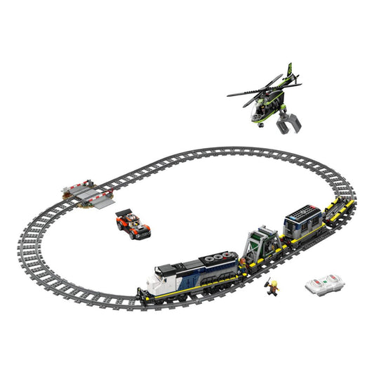 A toy construction set featuring a curved gray train track with a blue and white locomotive, a cargo car, a small orange vehicle, a green and black helicopter, a bridge, and a minifigure, all arranged on a plain white background.