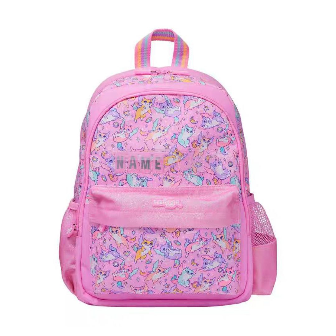 A pink backpack with a repeating unicorn pattern, featuring a front zippered pocket with a pink name patch, side mesh pockets, and a top carrying handle on a white background.