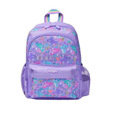 A purple backpack featuring a colorful cartoon character pattern on the main body and front pocket, with a rainbow-colored top handle and a clear side mesh pocket, shown on a plain white background.