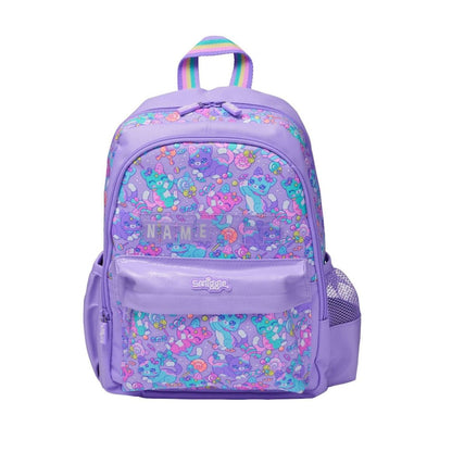 A purple backpack featuring a colorful cartoon character pattern on the main body and front pocket, with a rainbow-colored top handle and a clear side mesh pocket, shown on a plain white background.