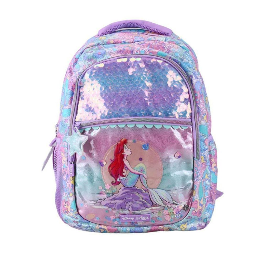A Disney Ariel mermaid backpack featuring a large iridescent sequin front pocket, a clear front window showing Ariel, and purple trim, set against a plain white background.